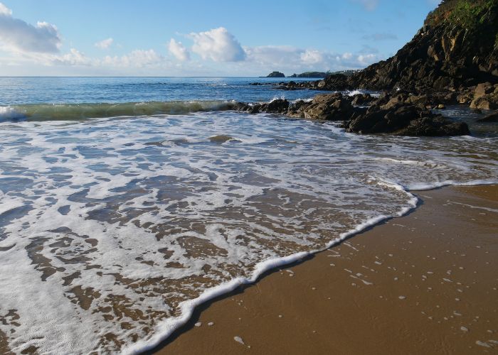 Vue du fort de Bertheaume depuis la plage de Porsmilin, départ des randonnées guidées Terre d'écume on voit l'écume des vagues sur la plage.