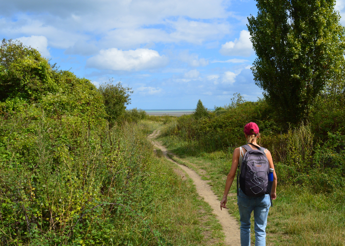 Fanny Peyrard est prise en photo de dos sur le sentier côtier GR34 pour illustrer les randonnées guidées Terre d'écume.